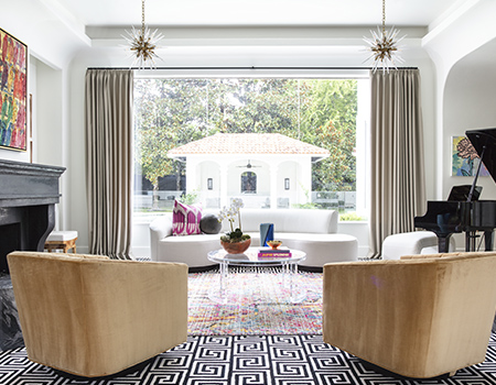 Living room with modern black and while inlay tile with two tan chairs and glass chandeliers with oversized window in the background leading to the backyard in Houston, TX